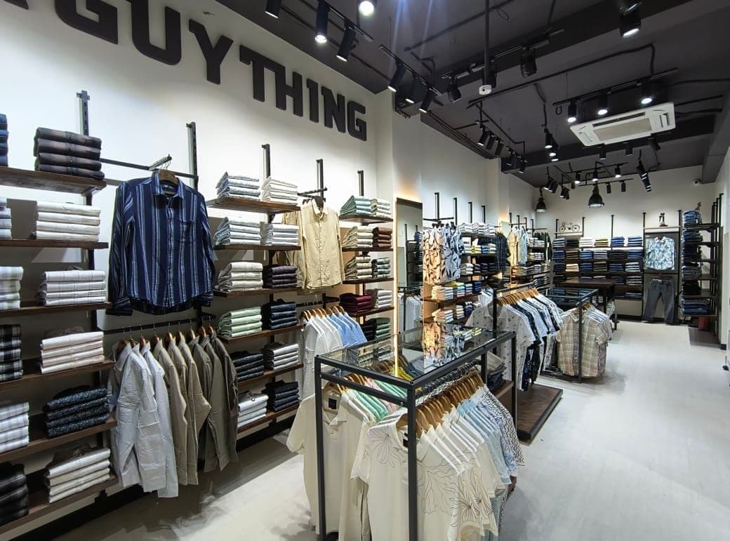 The menswear floor of Urban Closet, Guwahati: shirt bays along the wall and a glass display island